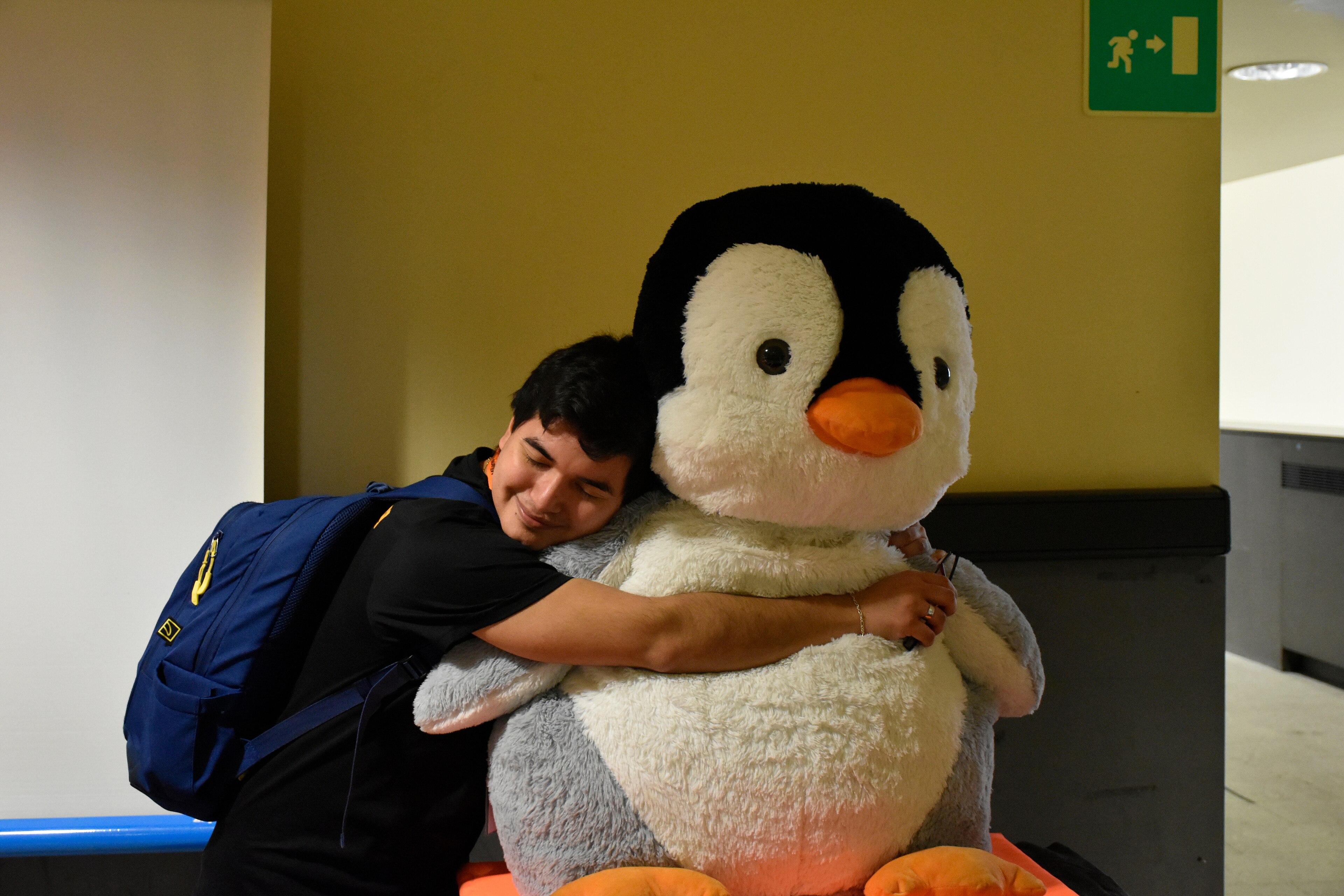 Учасник Linux Day обіймає великого Tux — символ Linux
